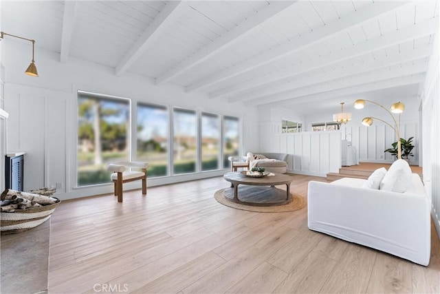 living room featuring a notable chandelier, beam ceiling, and light hardwood / wood-style floors