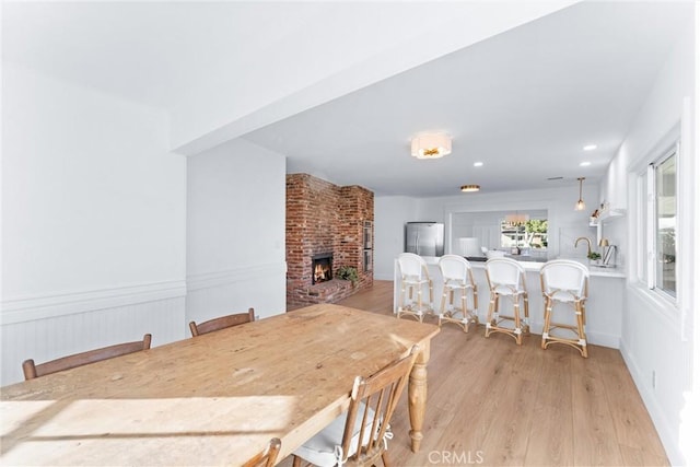 dining area with a brick fireplace and light wood-type flooring