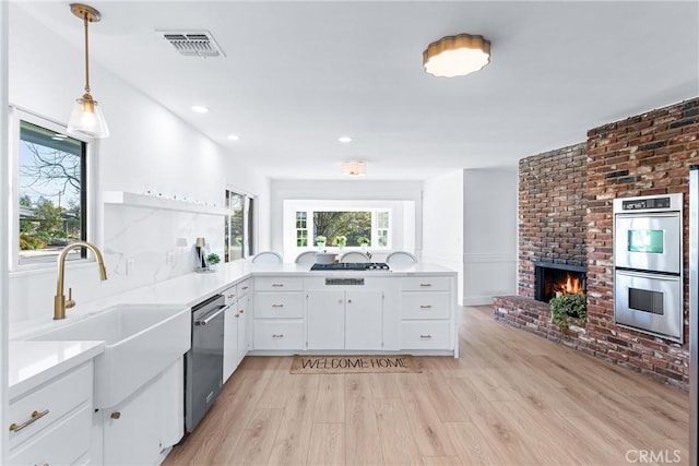 kitchen featuring appliances with stainless steel finishes, decorative light fixtures, light hardwood / wood-style flooring, and white cabinets