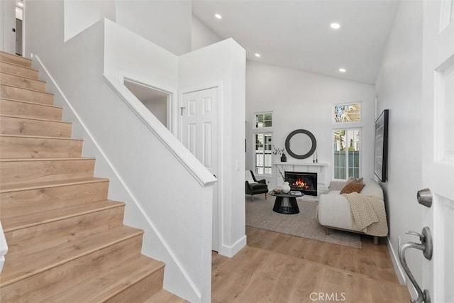 staircase with a fireplace, hardwood / wood-style floors, and a high ceiling