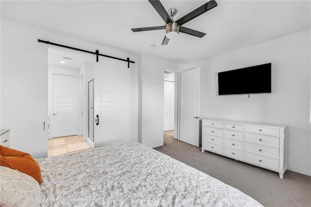 bedroom featuring light carpet, a barn door, and a ceiling fan