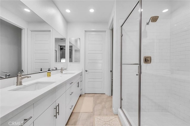 bathroom featuring double vanity, a stall shower, a sink, and recessed lighting