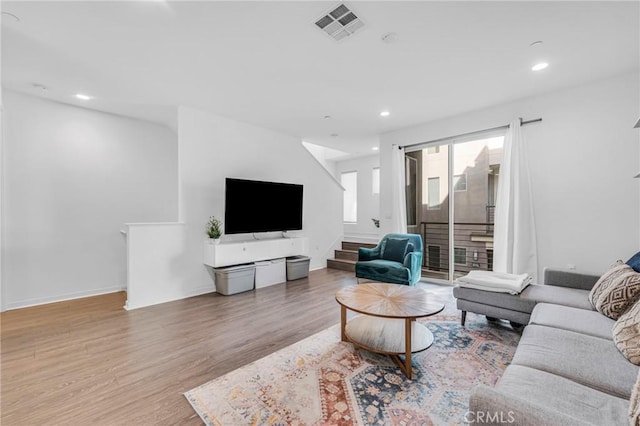 living area with recessed lighting, wood finished floors, visible vents, baseboards, and stairway