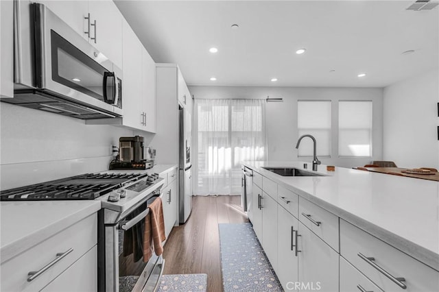 kitchen with white cabinets, appliances with stainless steel finishes, light countertops, and a sink