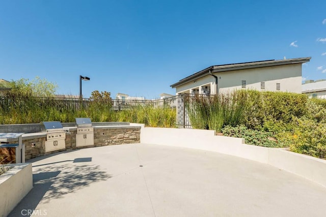 view of patio featuring area for grilling, an outdoor kitchen, and fence