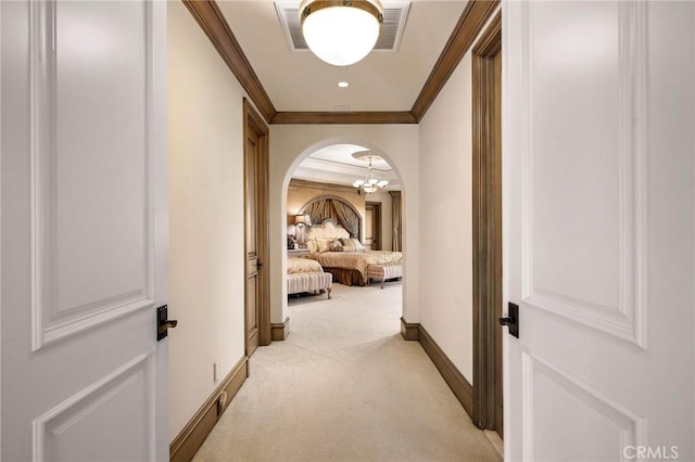 hall with ornamental molding and light colored carpet