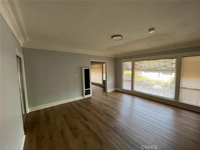 spare room featuring dark wood-type flooring, ornamental molding, and a textured ceiling