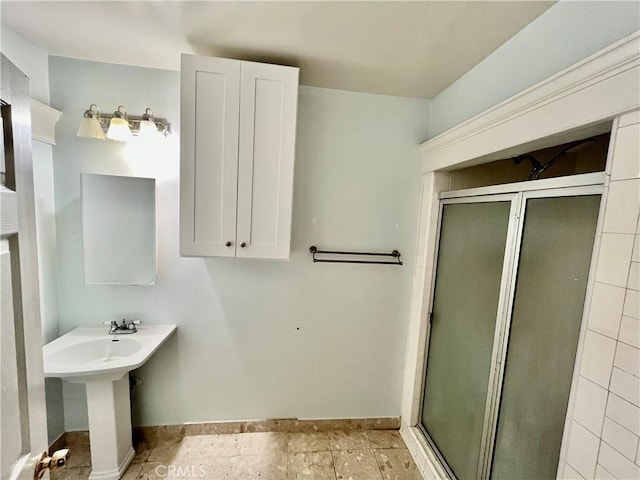 1143 S Manhattan Pl, Los Angeles, CA 90019 - bathroom featuring a stall shower, baseboards, and a sink