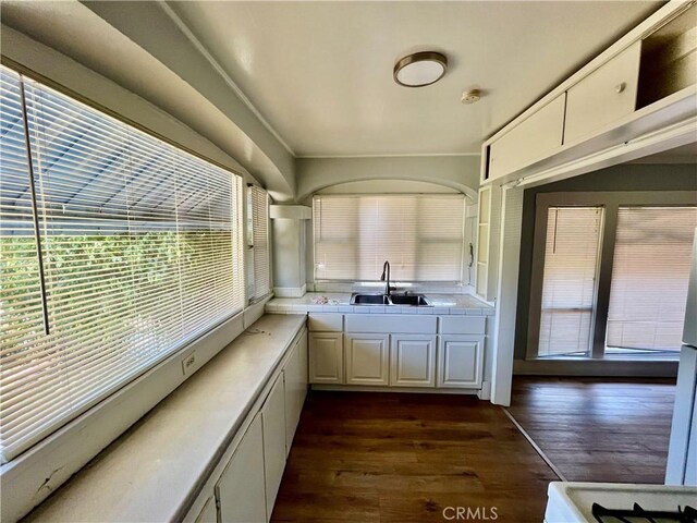 1143 S Manhattan Pl, Los Angeles, CA 90019 - kitchen with a sink, tile counters, dark wood finished floors, and white cabinets