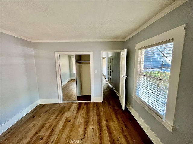 1143 S Manhattan Pl, Los Angeles, CA 90019 - unfurnished bedroom with ornamental molding, wood finished floors, baseboards, a closet, and a textured ceiling