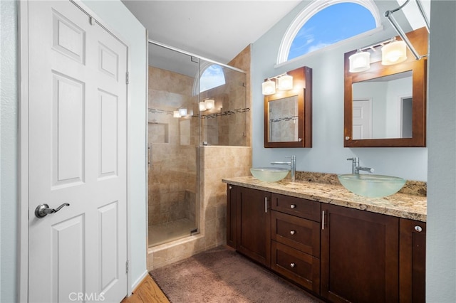 bathroom featuring hardwood / wood-style floors, vanity, and a tile shower