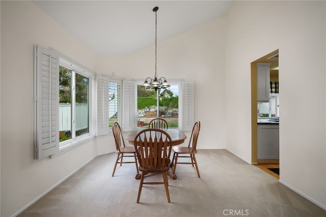 dining space with light carpet, a notable chandelier, and high vaulted ceiling