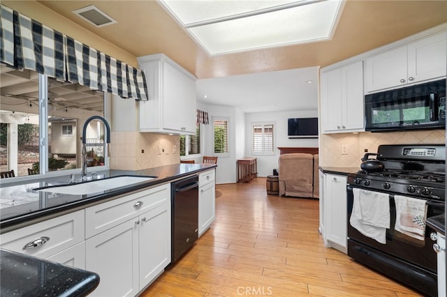 kitchen featuring sink, black appliances, light hardwood / wood-style flooring, white cabinets, and backsplash