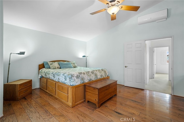 bedroom with lofted ceiling, light hardwood / wood-style floors, an AC wall unit, and ceiling fan