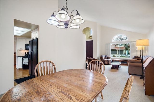 dining area featuring light carpet, vaulted ceiling, and a chandelier