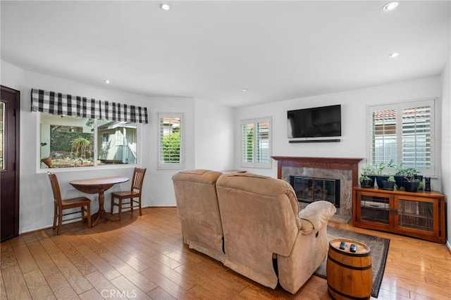 living room featuring a healthy amount of sunlight, a fireplace, and light wood-type flooring