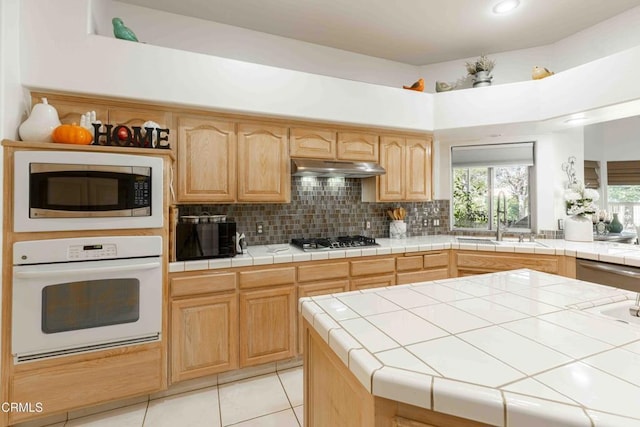 kitchen featuring sink, backsplash, tile counters, and stainless steel appliances