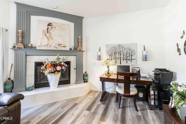 home office with hardwood / wood-style flooring and a tile fireplace