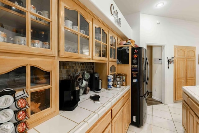 interior space featuring tasteful backsplash, fridge, tile counters, and light tile patterned floors