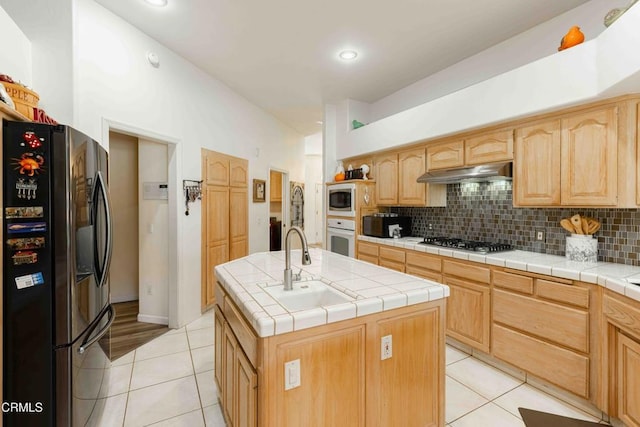 kitchen featuring appliances with stainless steel finishes, a kitchen island with sink, tile counters, and decorative backsplash