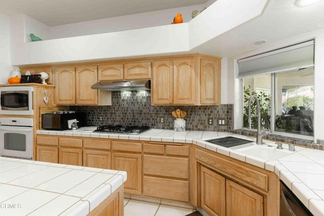 kitchen featuring stainless steel appliances, sink, tile countertops, and backsplash