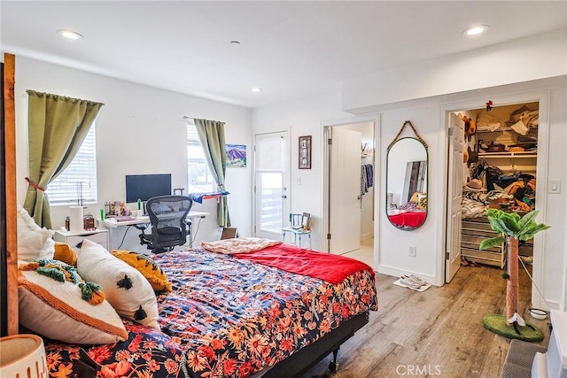 bedroom featuring a walk in closet, a closet, and light wood-type flooring