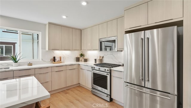 kitchen with tasteful backsplash, light hardwood / wood-style flooring, and appliances with stainless steel finishes