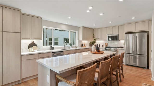 kitchen featuring a breakfast bar, sink, a center island, stainless steel appliances, and decorative backsplash