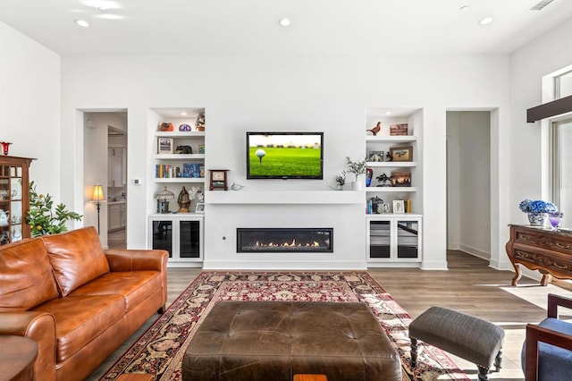 living room with hardwood / wood-style floors and built in shelves