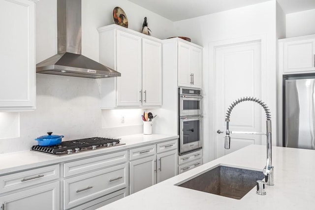 kitchen with white cabinetry, sink, wall chimney exhaust hood, and appliances with stainless steel finishes