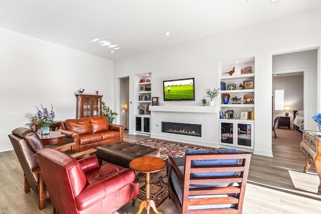 living room featuring wood-type flooring and built in shelves