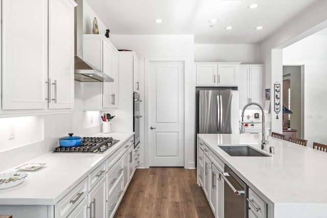 kitchen with sink, dark wood-type flooring, appliances with stainless steel finishes, white cabinetry, and a kitchen island with sink