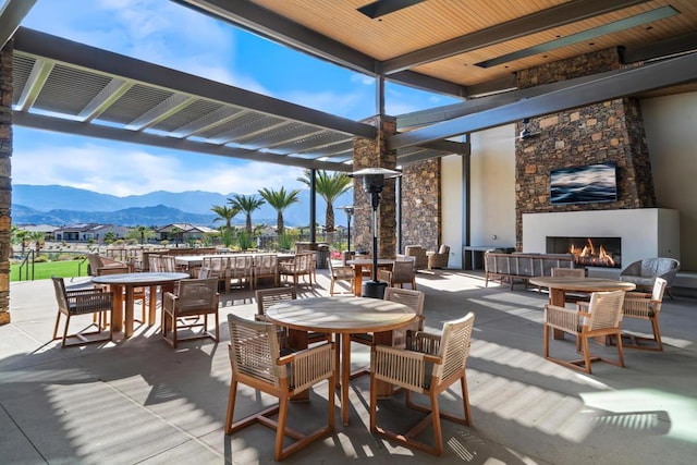 view of patio featuring a mountain view and an outdoor stone fireplace