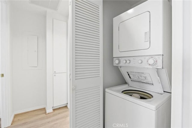 clothes washing area with stacked washer and clothes dryer, electric panel, and light hardwood / wood-style flooring