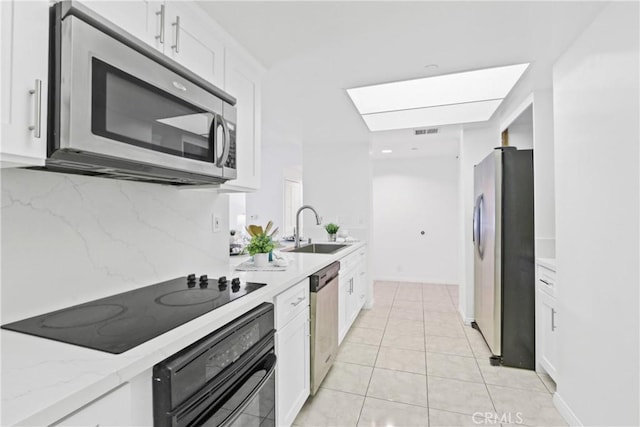 kitchen featuring white cabinetry, light stone countertops, sink, and black appliances