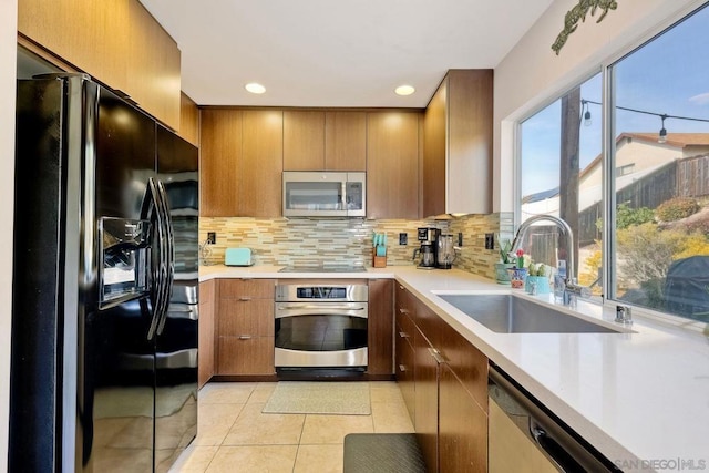 kitchen featuring tasteful backsplash, light tile patterned floors, sink, and black appliances