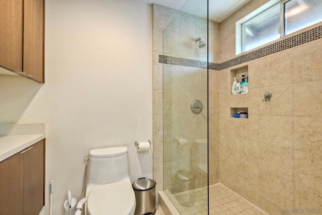 bathroom with a tile shower and toilet