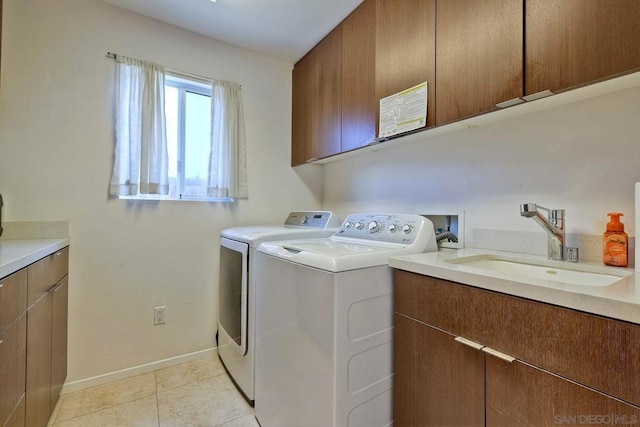 laundry room with cabinets, washer and clothes dryer, sink, and light tile patterned floors