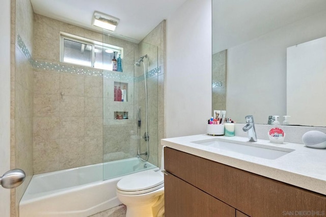 full bathroom featuring tiled shower / bath, vanity, and toilet