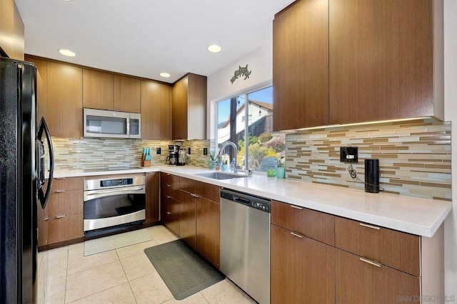 kitchen with light tile patterned flooring, sink, decorative backsplash, and black appliances