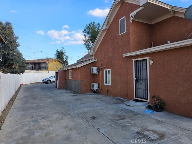 view of home's exterior with a wall mounted air conditioner and a patio