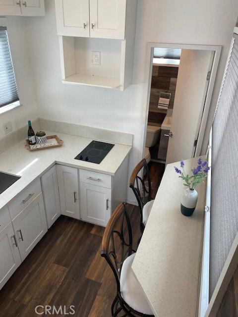 kitchen featuring white cabinetry, a kitchen breakfast bar, black electric cooktop, and dark hardwood / wood-style floors