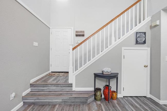 stairs with hardwood / wood-style floors and a high ceiling