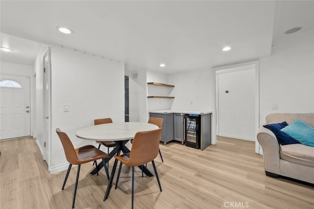 dining area featuring bar, beverage cooler, and light hardwood / wood-style flooring