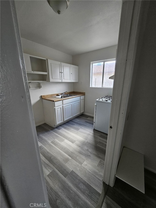 kitchen with sink, white cabinetry, wooden counters, white gas range oven, and light hardwood / wood-style floors