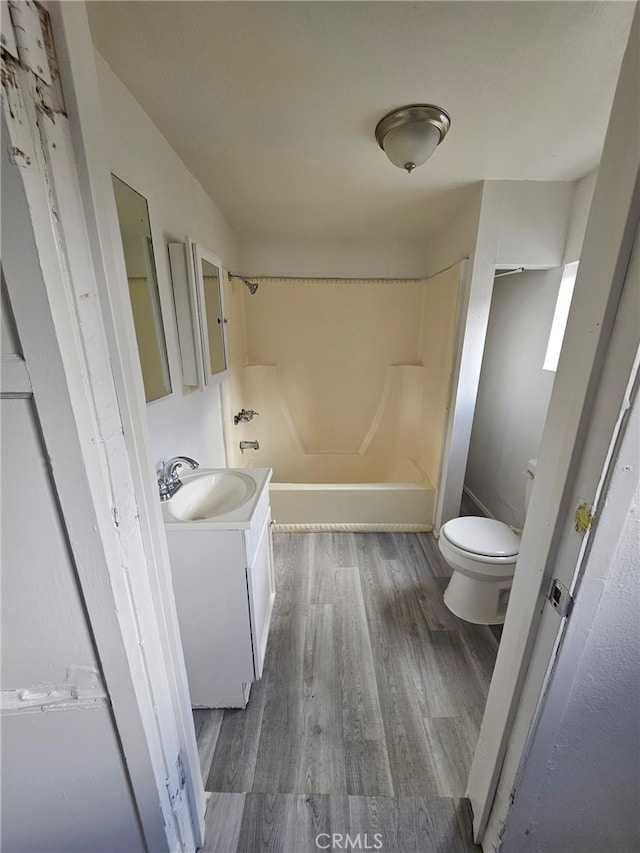 full bathroom featuring shower / washtub combination, toilet, wood-type flooring, and vanity