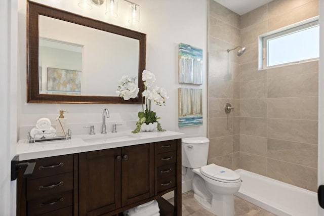 bathroom with vanity, tiled shower, and toilet