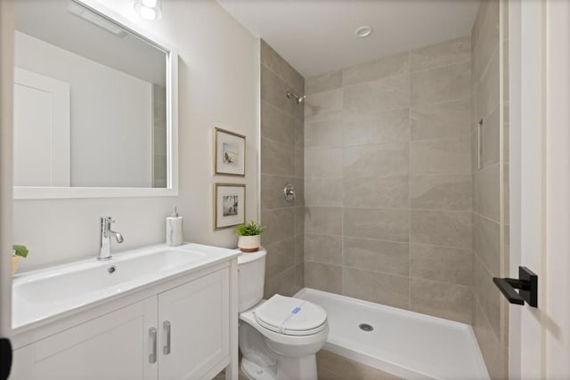 bathroom featuring vanity, toilet, and tiled shower