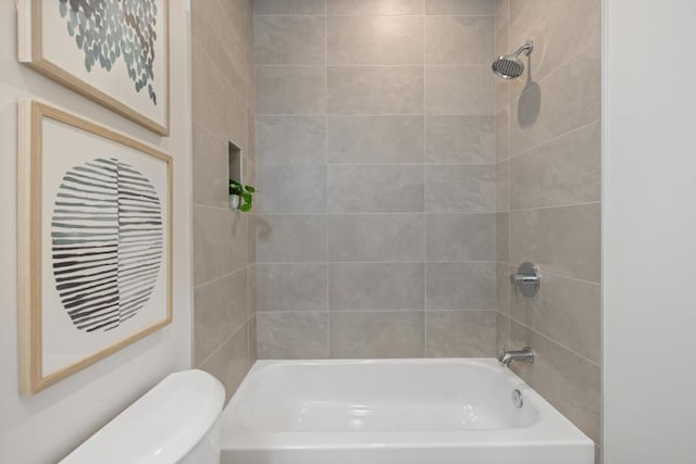 bathroom with tiled shower / bath combo and toilet