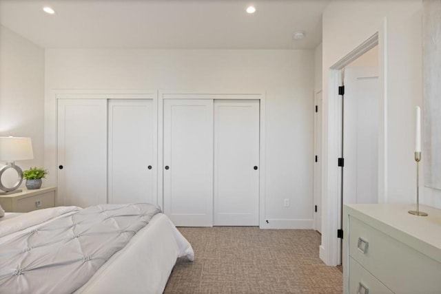 bedroom with multiple closets and light colored carpet